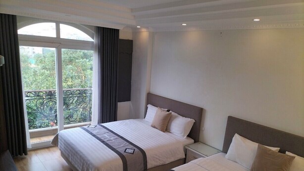 A hotel room with two beds, a balcony, and a view of greenery. - Sao Mai Cosy Nest Noi Bai Airport (Hanoi)