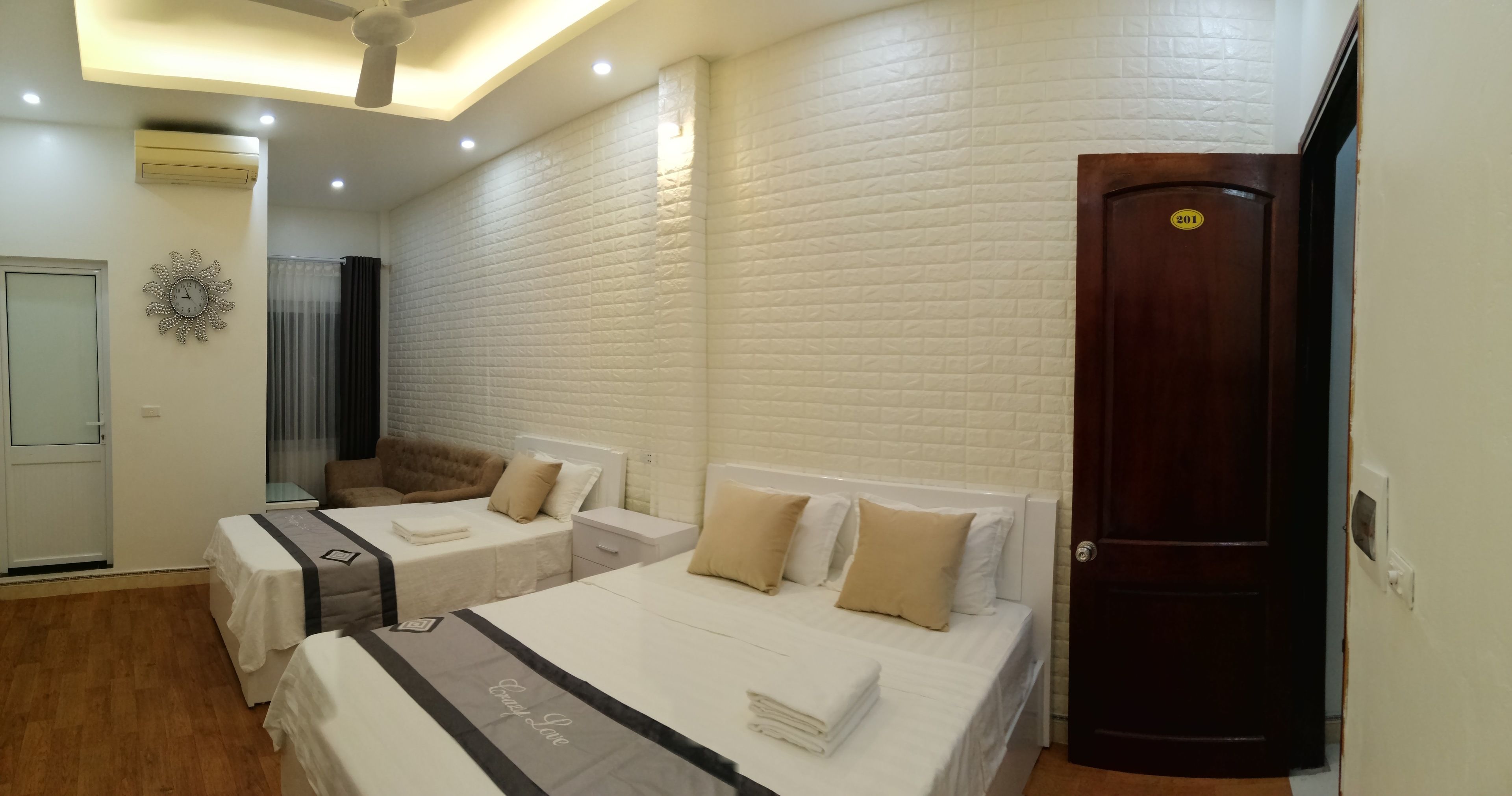 Una habitación de hotel con dos camas, un ventilador de techo y una puerta de madera.