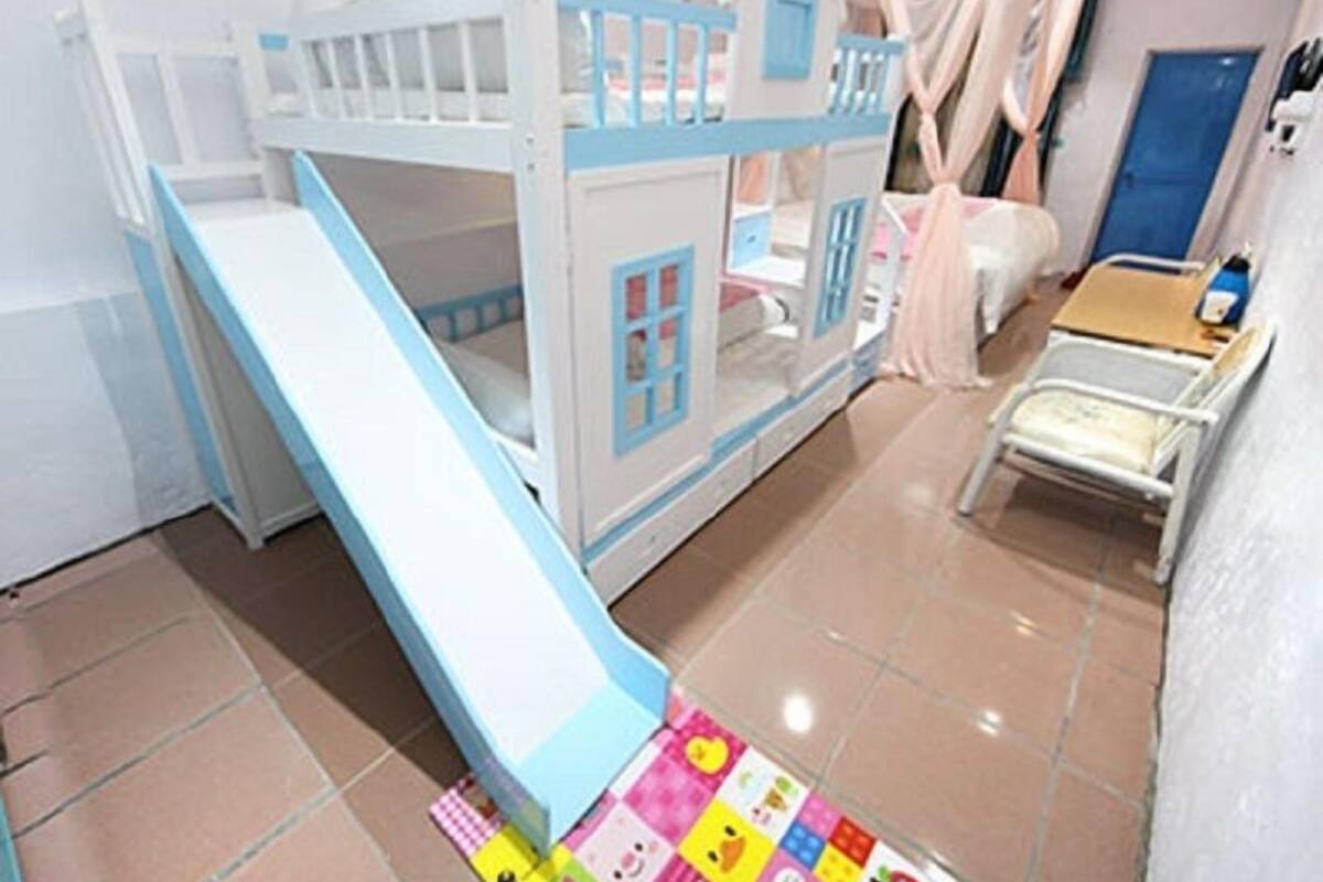 A bunk bed with a slide, a bedside table, and a chair.