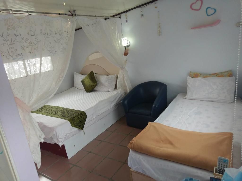 A bedroom with two beds, a chair, and a bedside table.