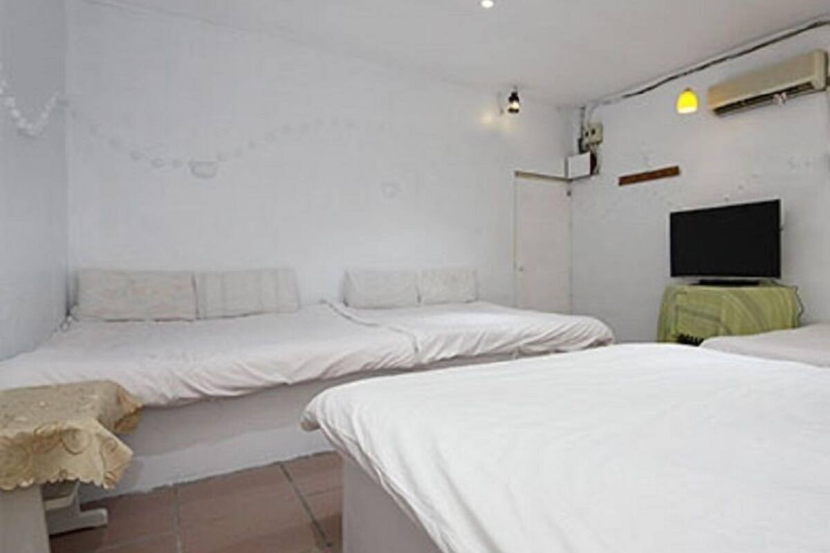 A room with two beds, a television, and a small table with a green tablecloth.