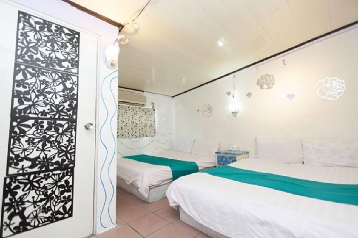 A hotel room with two beds, a decorative door, and a wall with a floral pattern.
