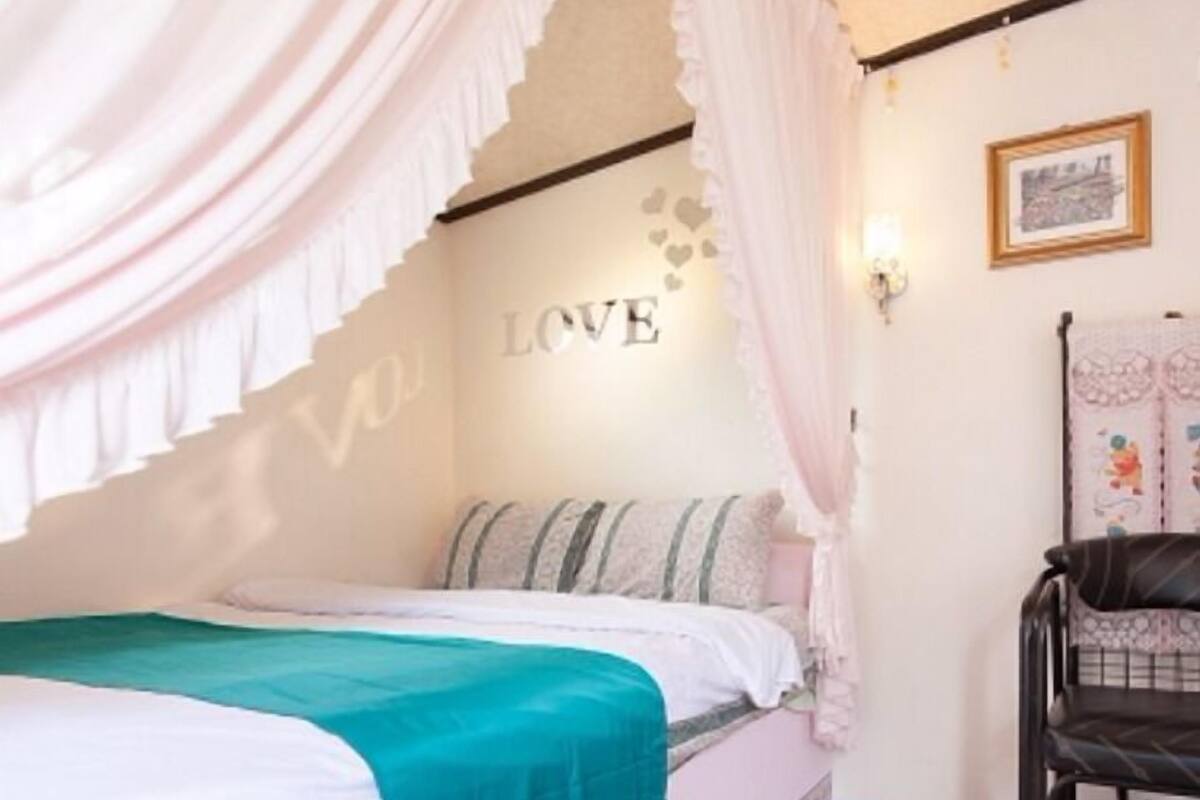 A bedroom with a bed, a chair, and a wall with the word "LOVE".