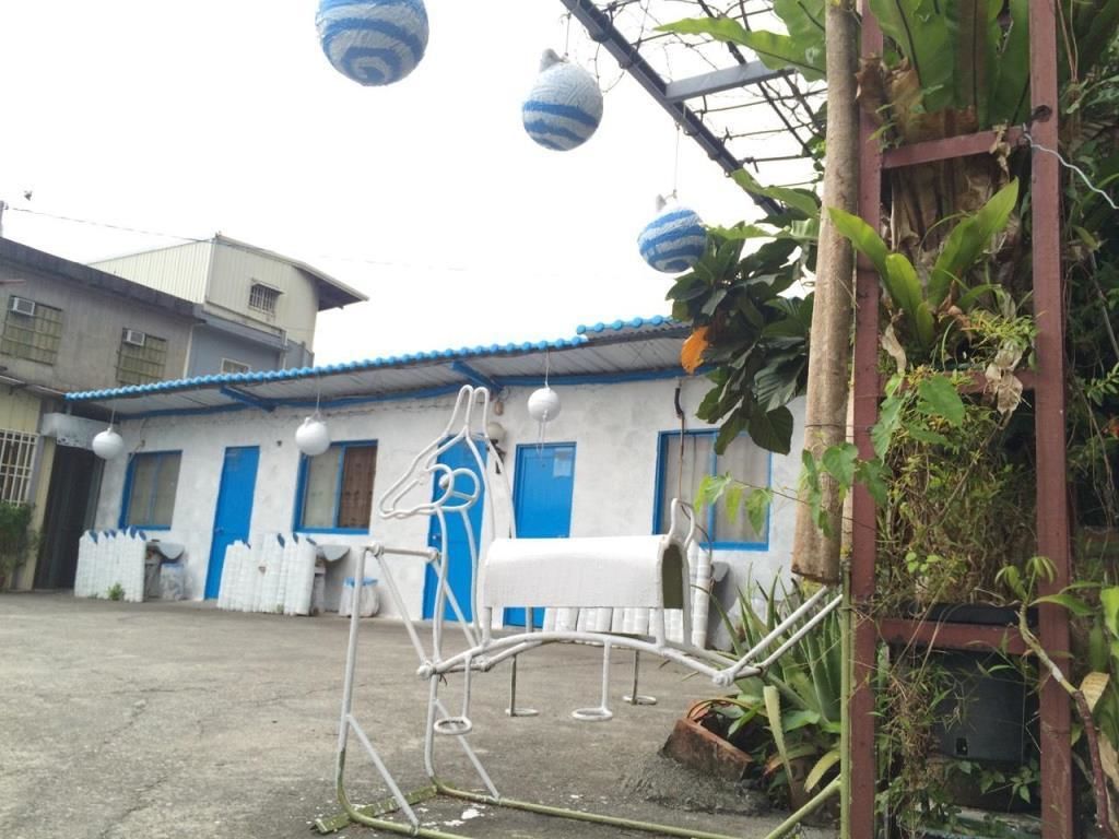 A courtyard with a white metal chair, a white mailbox, and blue-striped hanging lanterns.