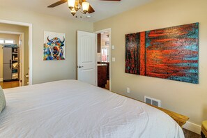 Une chambre à coucher avec un grand lit, un ventilateur de plafond et deux tableaux accrochés au mur.