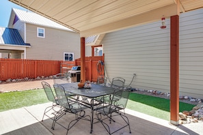 Une terrasse extérieure avec une table et des chaises, un barbecue et une clôture en bois.