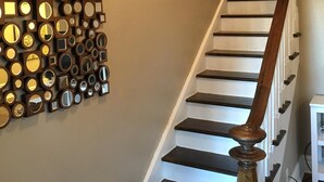 Un escalier doté d’une rampe en bois et d’un mur orné d’une collection de miroirs.