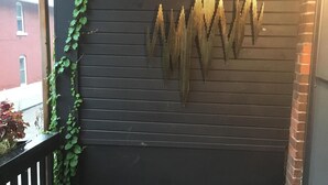 Un mur en bois foncé agrémenté d’un élément décoratif en métal et d’une rambarde noire ornée de plantes.