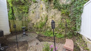 Un espace extérieur pavé, avec un chemin en briques, une clôture en bois et un banc en pierre.