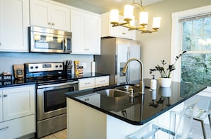 A modern kitchen with stainless steel appliances, a black granite countertop, and a built-in sink.