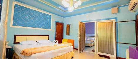 A hotel room with a bed, a chandelier, a door, and a window.