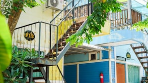 Un edificio de varios pisos con una escalera que conduce a los niveles superiores, rodeado de vegetación.