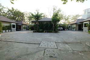 A courtyard with a central gazebo surrounded by potted plants and trees.