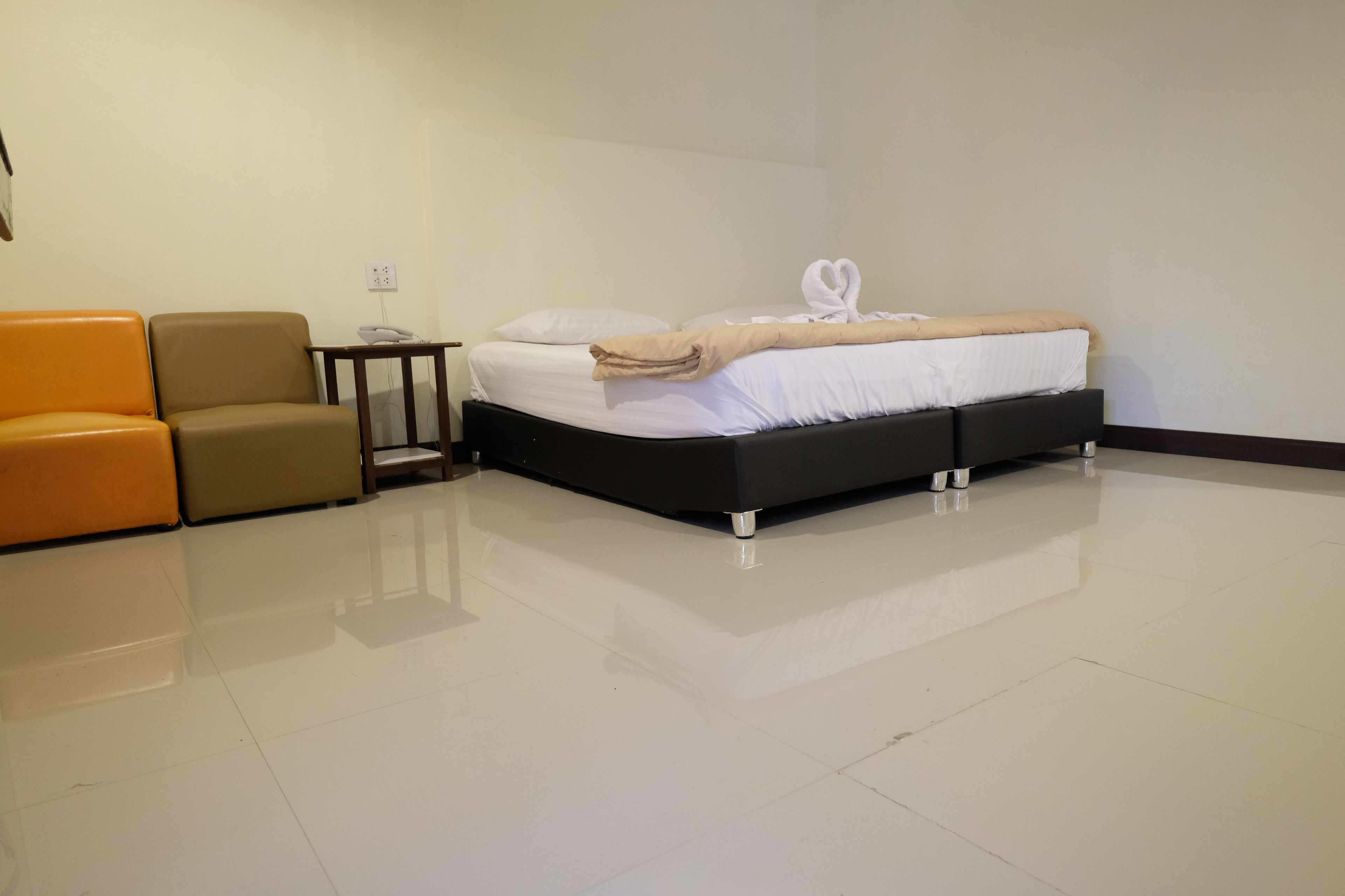 Una habitación de hotel con cama, mesita de noche, lámpara y un área de descanso con dos sillones.