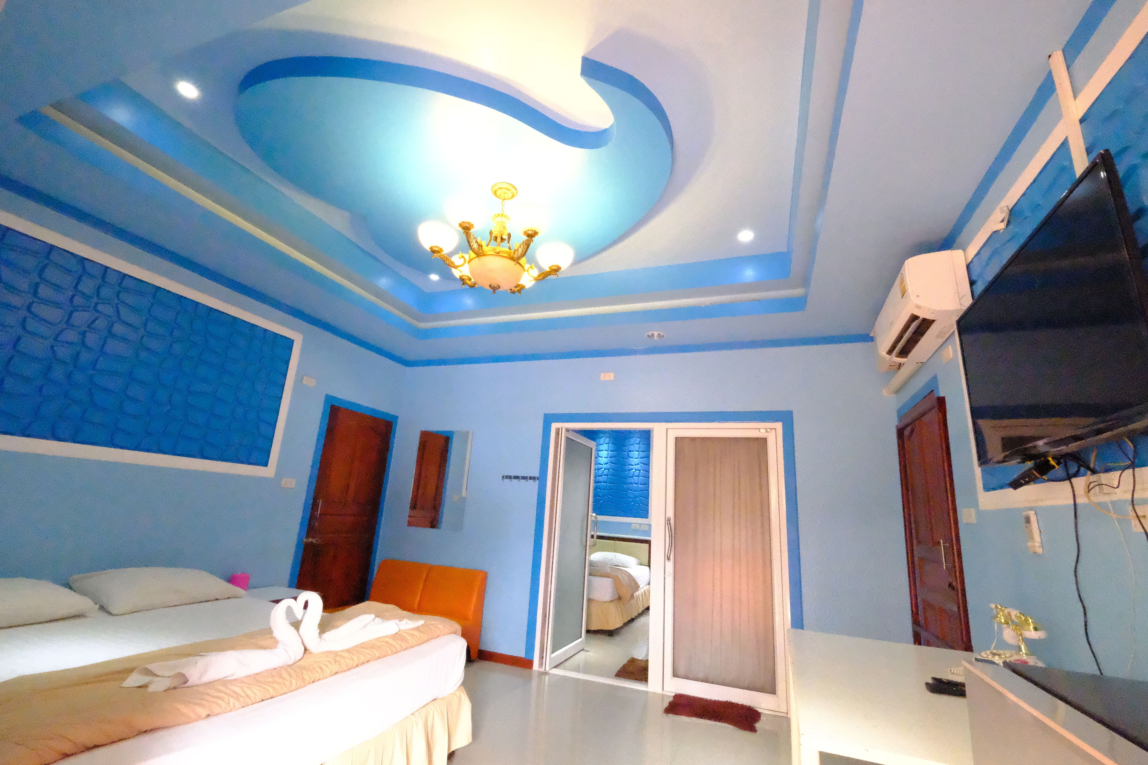 A hotel room with a bed, a desk, a television, and a ceiling with a unique design.