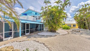 A resort with a blue building, palm trees, and a sandy courtyard.