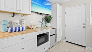 A modern kitchen with white cabinetry, a built-in microwave, and a coffee maker.