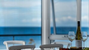Une table avec une bouteille de vin et deux verres, le tout placé devant un paysage marin pittoresque.
