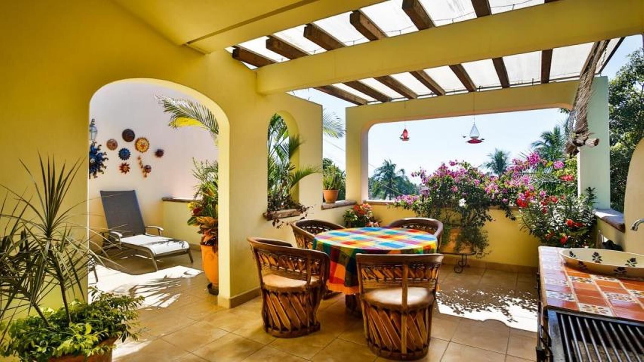 A sunlit patio with a round table, wicker chairs, and potted plants.