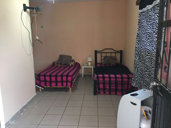 A small room with two beds, a nightstand, a lamp, and a radiator.