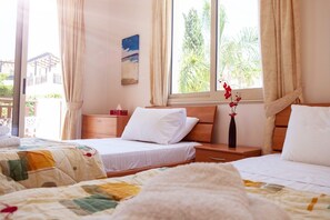 A hotel room with two beds, a window with curtains, a bedside table with a vase of flowers, and a painting on the wall. - Private Villa with own pool 5 minutes drive to Coral Bay with 2 Sandy beaches (Paphos)