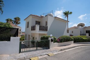 A two-story residential building with a balcony, satellite dish, and a gated entrance. - Private Villa with own pool 5 minutes drive to Coral Bay with 2 Sandy beaches (Paphos)