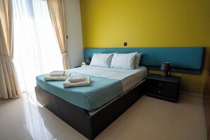 Une chambre d’hôtel avec un lit, des tables de chevet et une petite table de nuit.