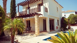 A two-story building with a balcony, a swimming pool, and outdoor seating.