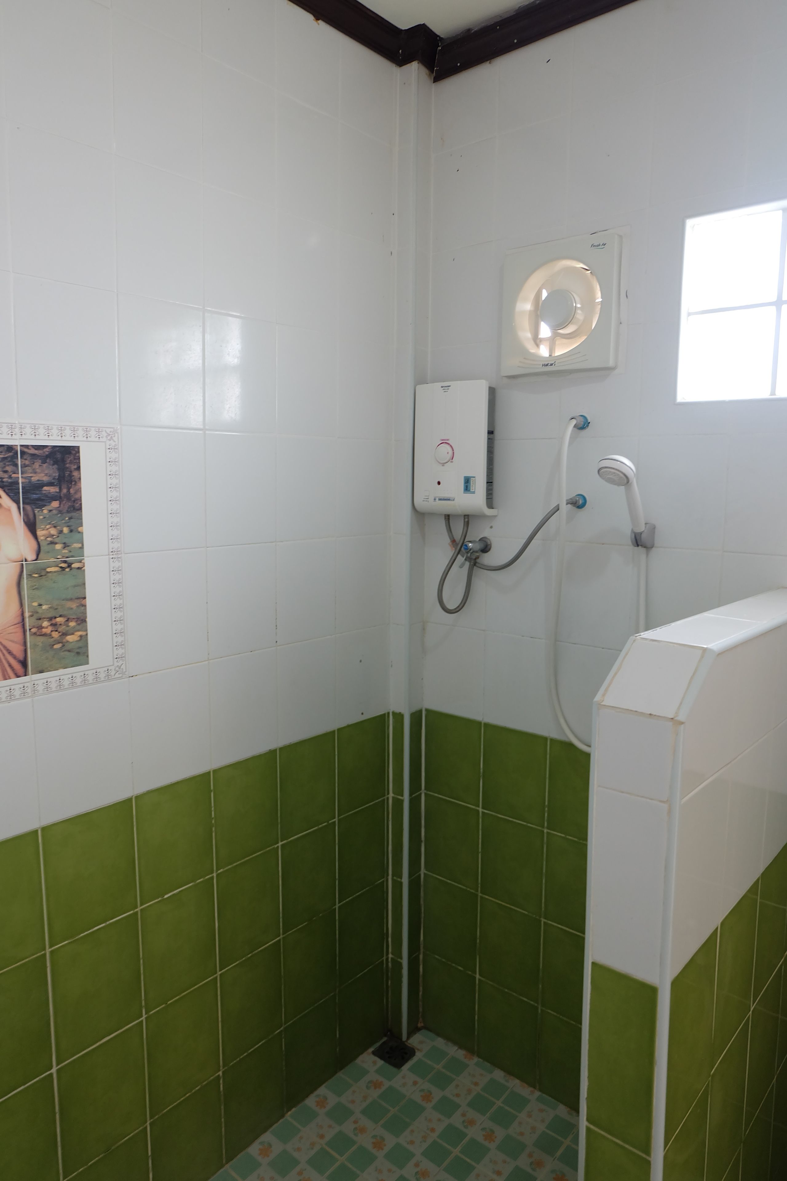 Un baño pequeño con azulejos, ducha, inodoro y ventana.