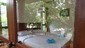A bedroom with a bed, pillows, and a blue towel. - Big Tree Resort (Kamphaeng Phet)
