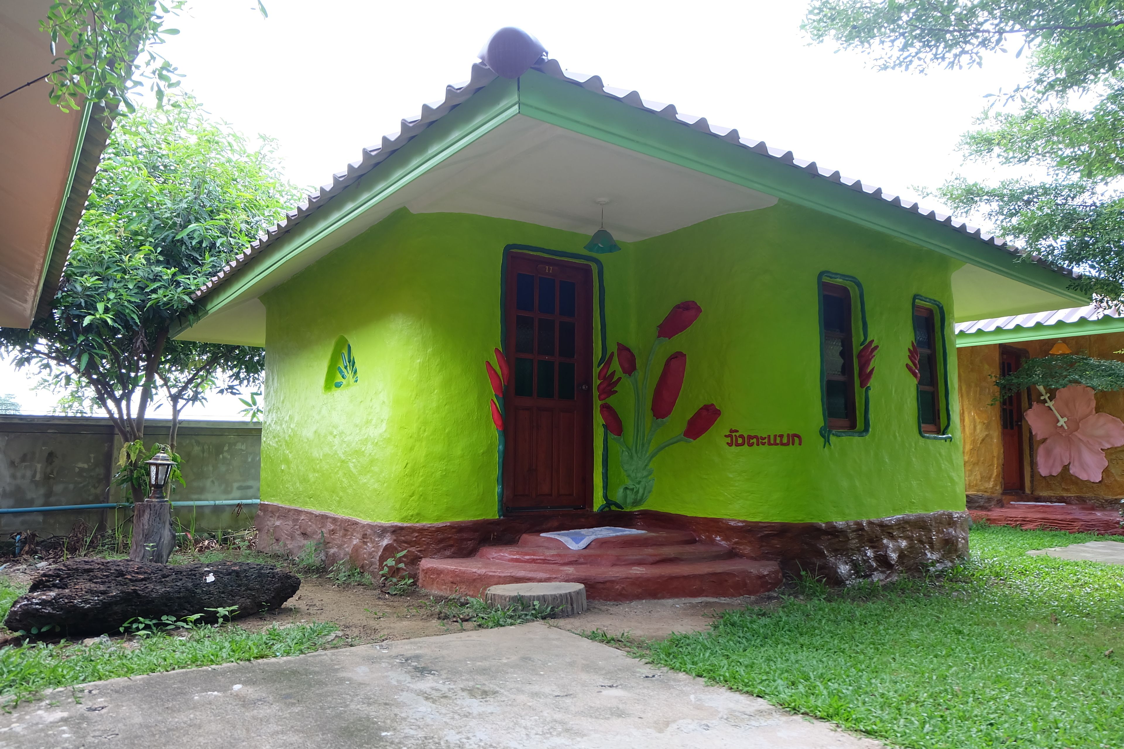 Une petite maison à un étage, avec une façade verte et une porte rouge.