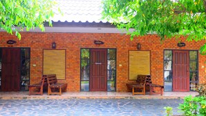 A brick building with two wooden doors and benches outside. - Big Tree Resort (Kamphaeng Phet)