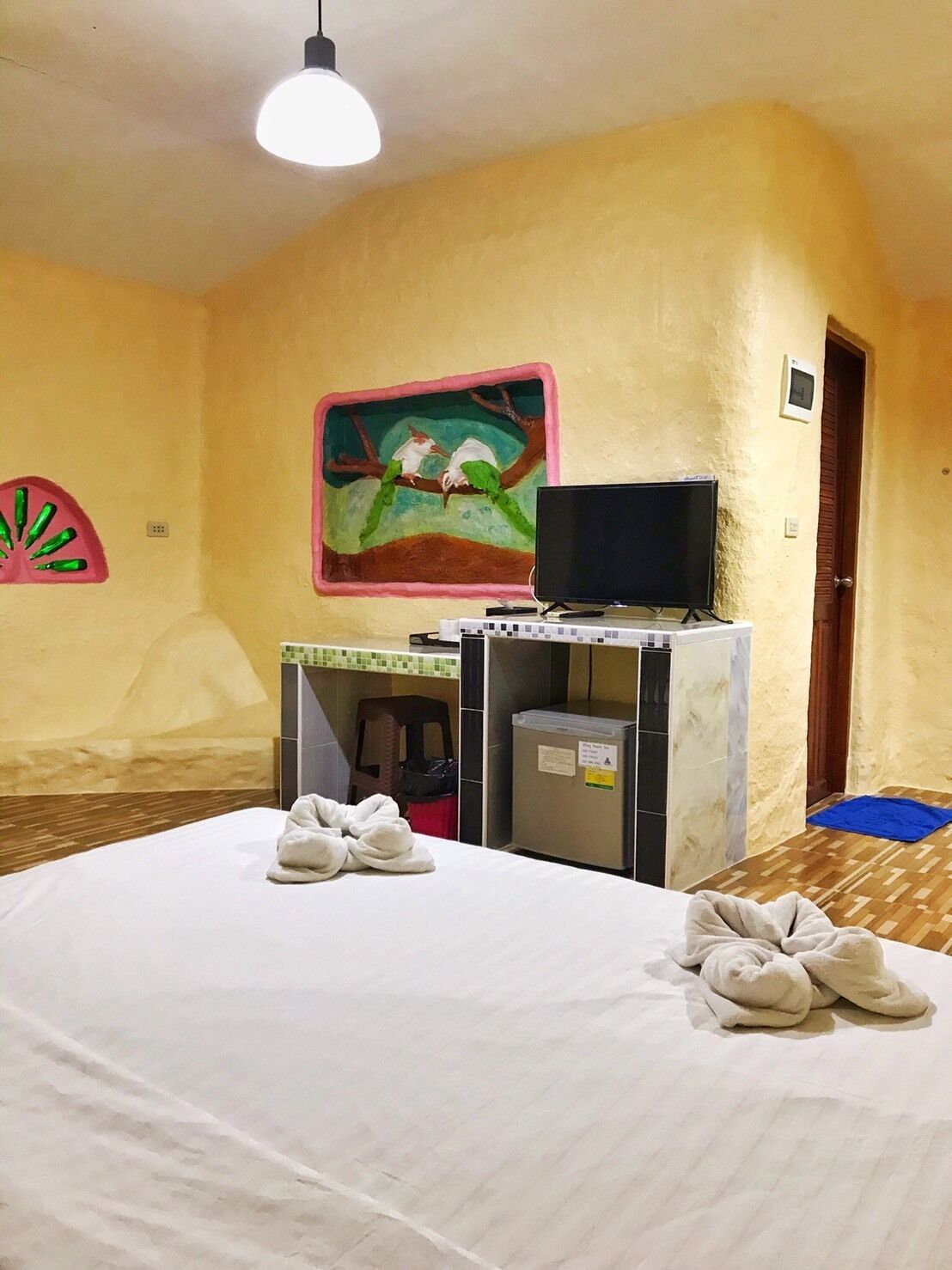 Habitación de hotel con cama, televisión, escritorio pequeño y un cuadro en la pared.