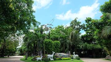 A park with a paved walkway, lush greenery, and white animal sculptures.