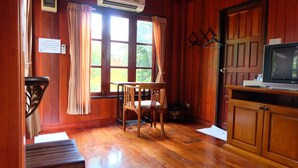 A wooden-paneled room with a dining table and chairs, a bench, a television, and an air conditioning unit. - Big Tree Resort (Kamphaeng Phet)