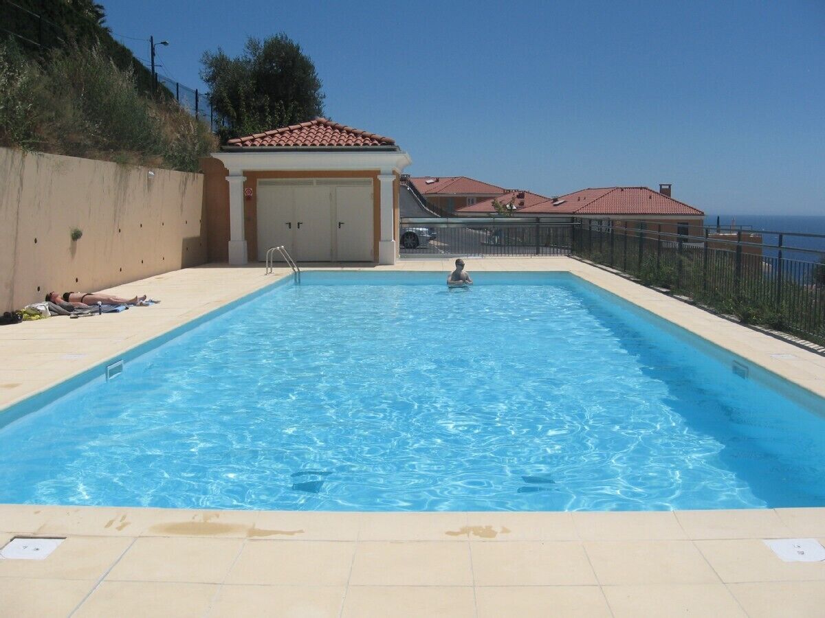 Ein rechteckiger Pool mit klarem, blauem Wasser, einem Sprungturm und einem Rettungsschwimmerstuhl.