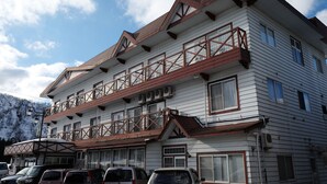 Hotel de diversos pisos d'arquitectura tradicional, amb balcons i una zona d'aparcament al davant.