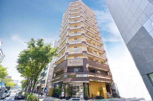 A multi-story hotel with a modern design, featuring balconies on each floor, a ground-level restaurant, and a parking area. - Eins Inn Umedahigashi (Osaka)