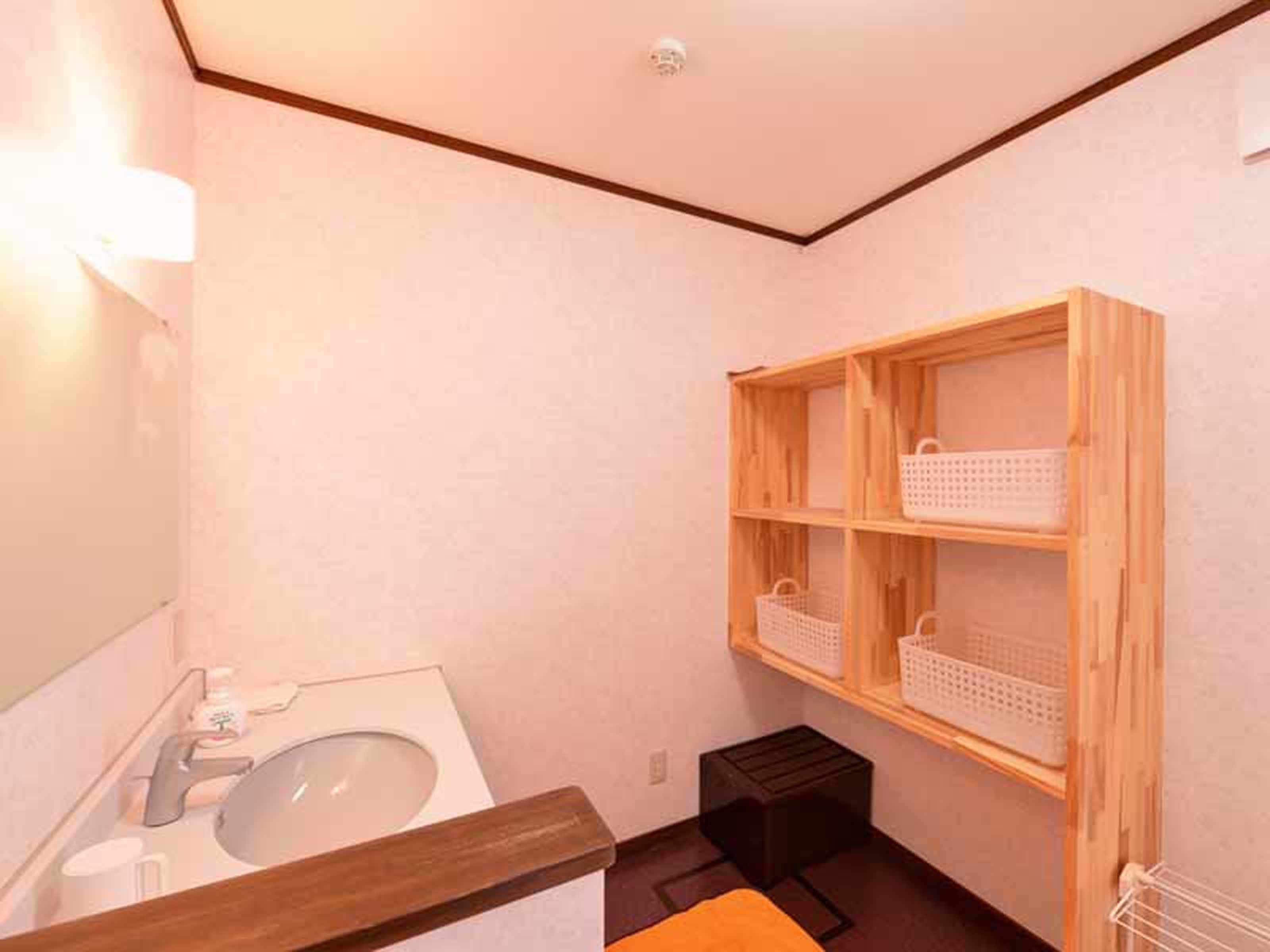 A bathroom with a wooden shelf unit, a sink, and a small stool.