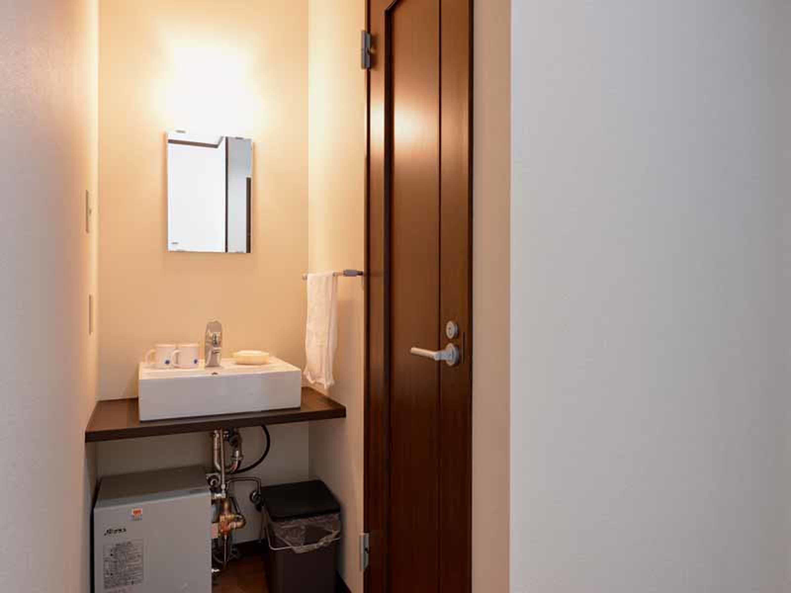 A small bathroom with a white sink, a mirror, and a wooden door.