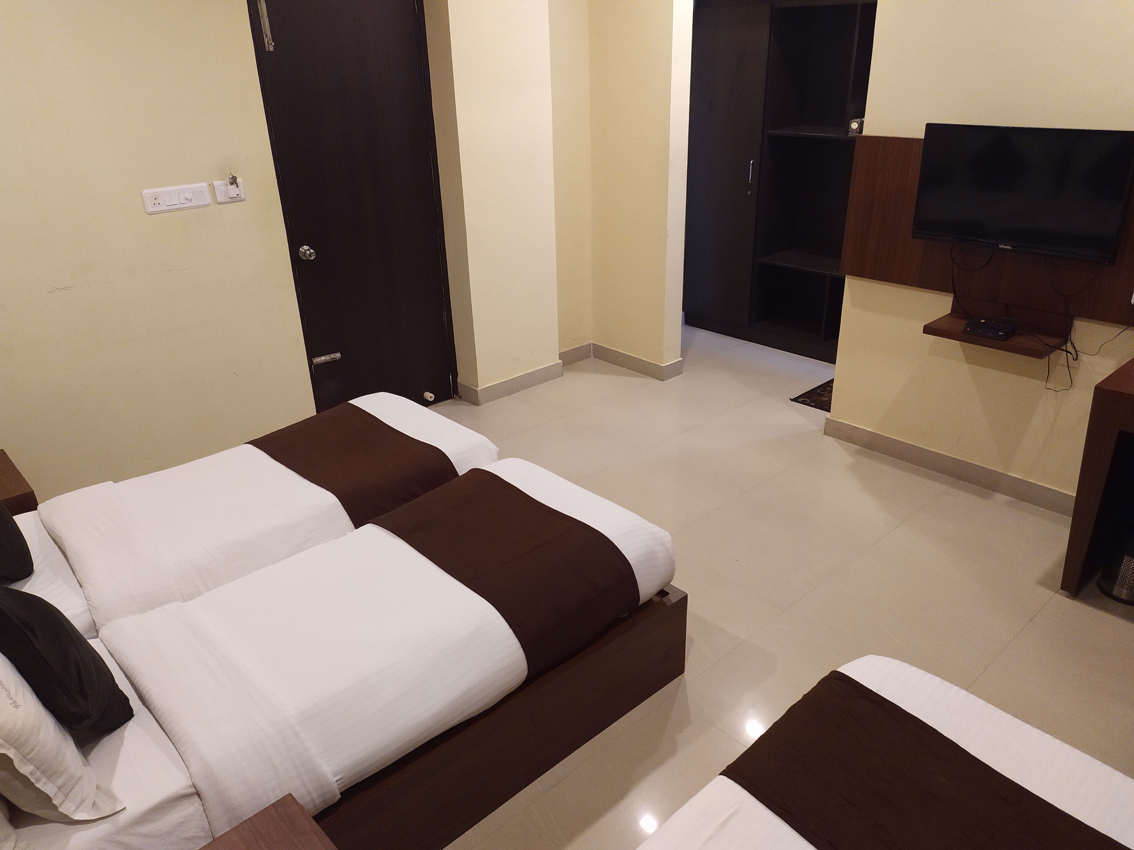 A hotel room with two beds, a TV, and a door.