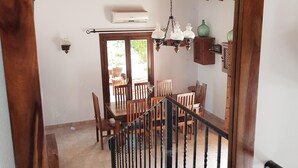 Vista enmarcada en madera de un comedor con candelabro, sillas de madera y una escalera.