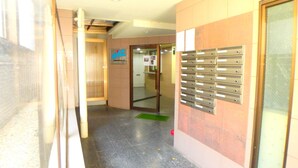 A hallway with a reception area, a glass door, and a wall-mounted mailbox. - Elitz INN Third (Kyoto)