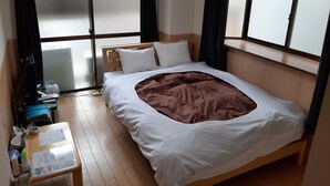 A hotel room with a bed, a small table with a menu, a TV, and a window with curtains. - Elitz INN Third (Kyoto)