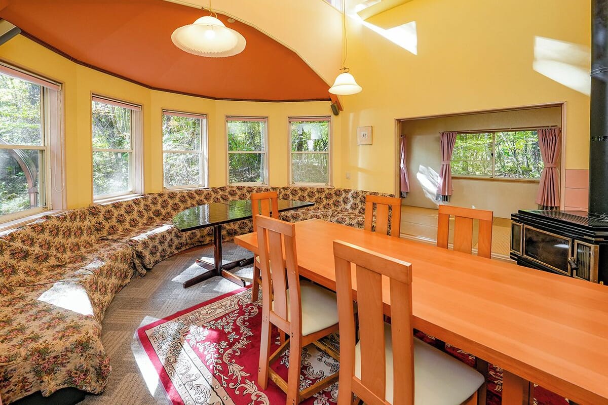 A cozy dining area with a long wooden table, matching chairs, and a built-in bench with floral upholstery.