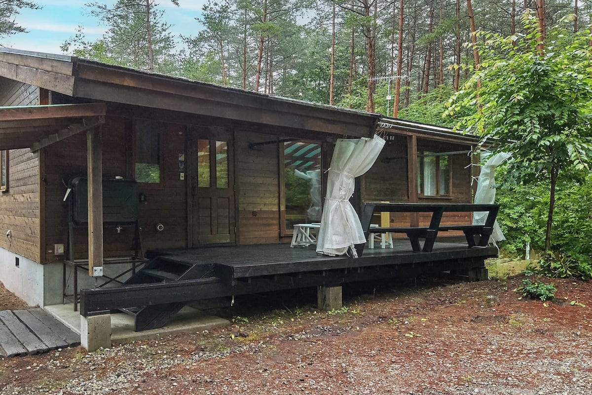 A cabin with a wooden exterior, a porch, and a covered seating area.