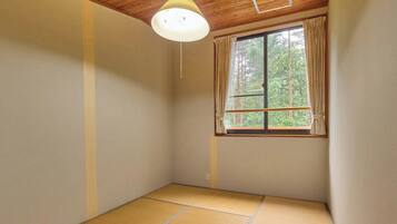 Una habitación con suelo de tatami, una ventana con cortinas y una lámpara en el techo.