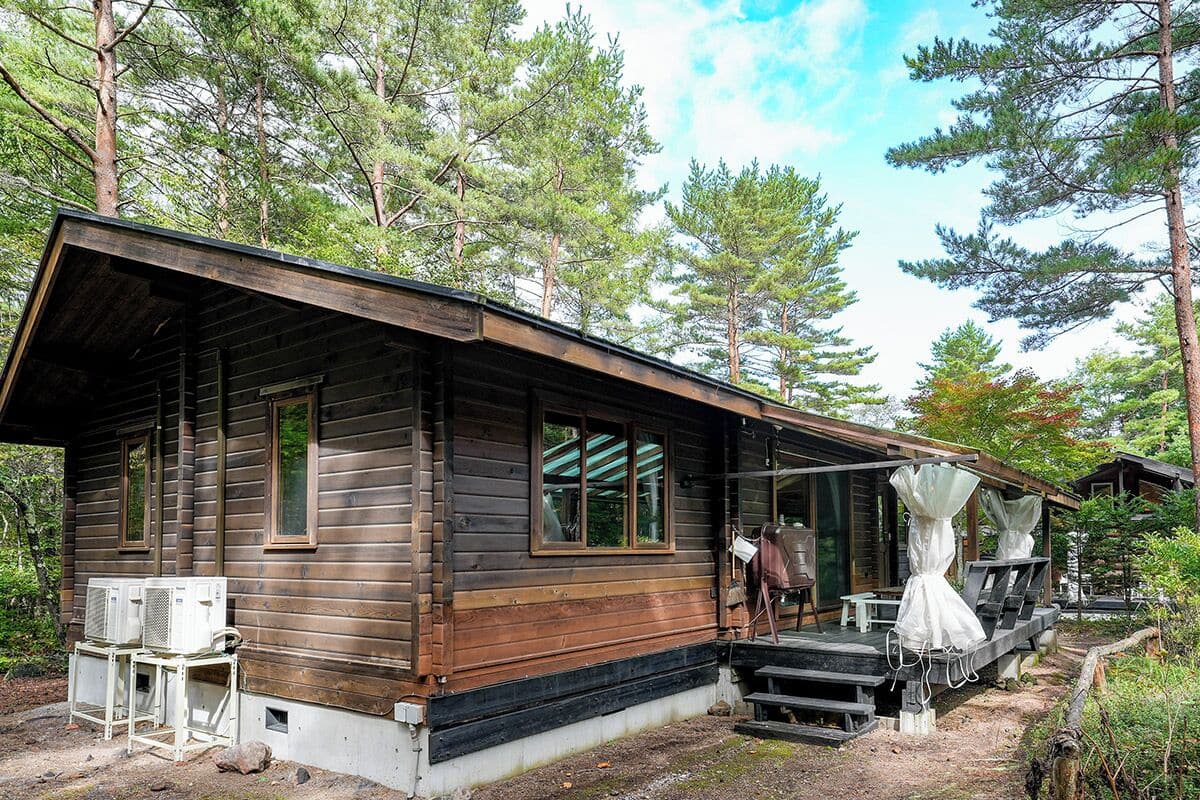 A rustic cabin with a porch, outdoor seating, and a covered area.