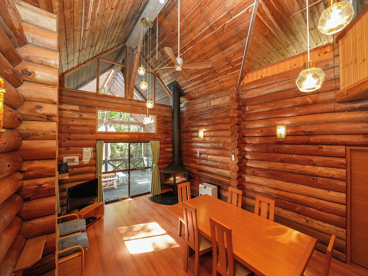 A log cabin interior with a dining area, a fireplace, and a television.