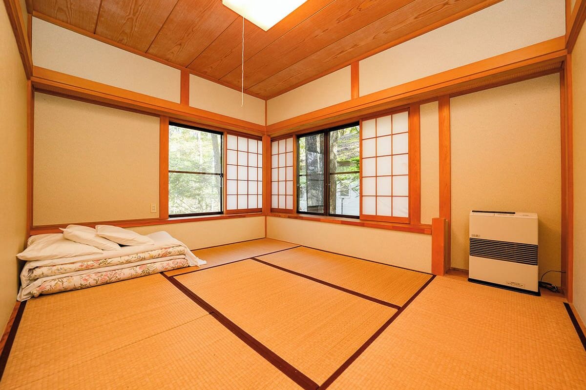 A traditional Japanese room with tatami flooring, shoji screens, and a futon bed.